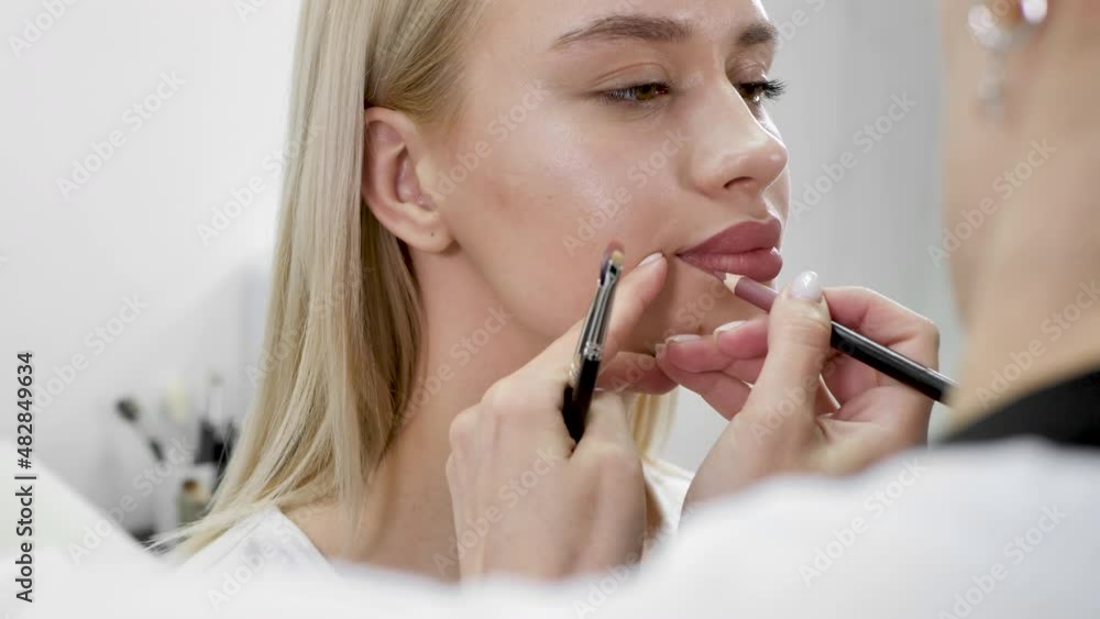 Lip makeup. Close-up of a cosmetologist painting her lips with a pencil before permanent makeup Lip makeup. Close-up of a cosmetologist painting her lips with a pencil before permanent makeup