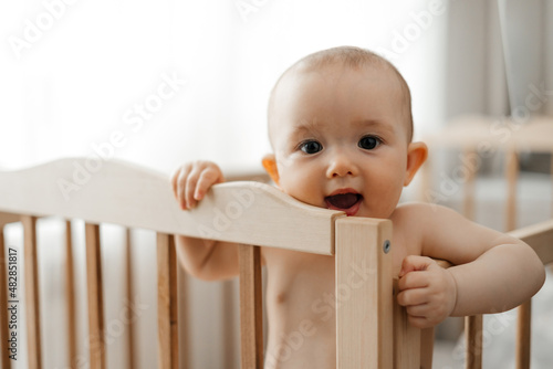 Фотография Portrait of a small child just starting to stand and hold on to the handrails in
