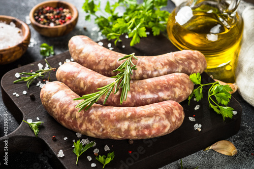 фотографія Bratwurst or sausages on cutting board with spices and herbs