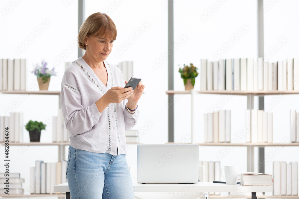 senior woman using smartphone for work in office senior woman using smartphone for work in office