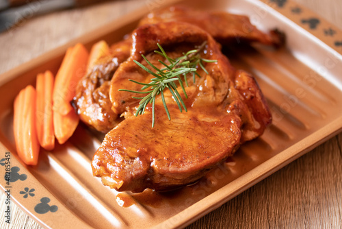 Meat during grilling. Chuck steak and rosemary garnished carrots.