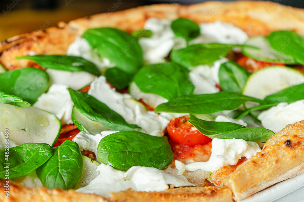 Pizza with spinach, zucchini slices, stracciatella cheese and tomatoes. Italian cuisine Pizza with spinach, zucchini slices, stracciatella cheese and tomatoes. Italian cuisine