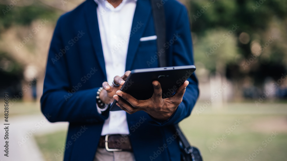 Close up of unrecognizable black business man using a tablet in a park downtown