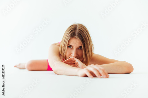 Beautiful athletic woman during training lies on a white cyclorama and looks at the camera.