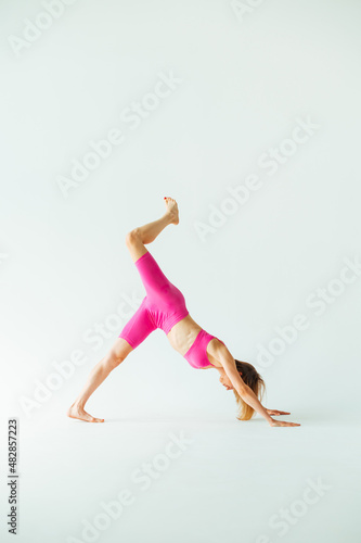 Sporty skinny woman in pink sportswear goes in for sports on a white background. Vertical.