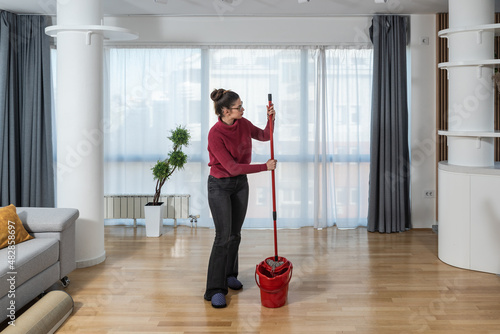 Wallpaper Mural Young woman cleaning her apartment floor with mop and wet wipe. Female doing housework and maintaining hygiene of clean home. Torontodigital.ca
