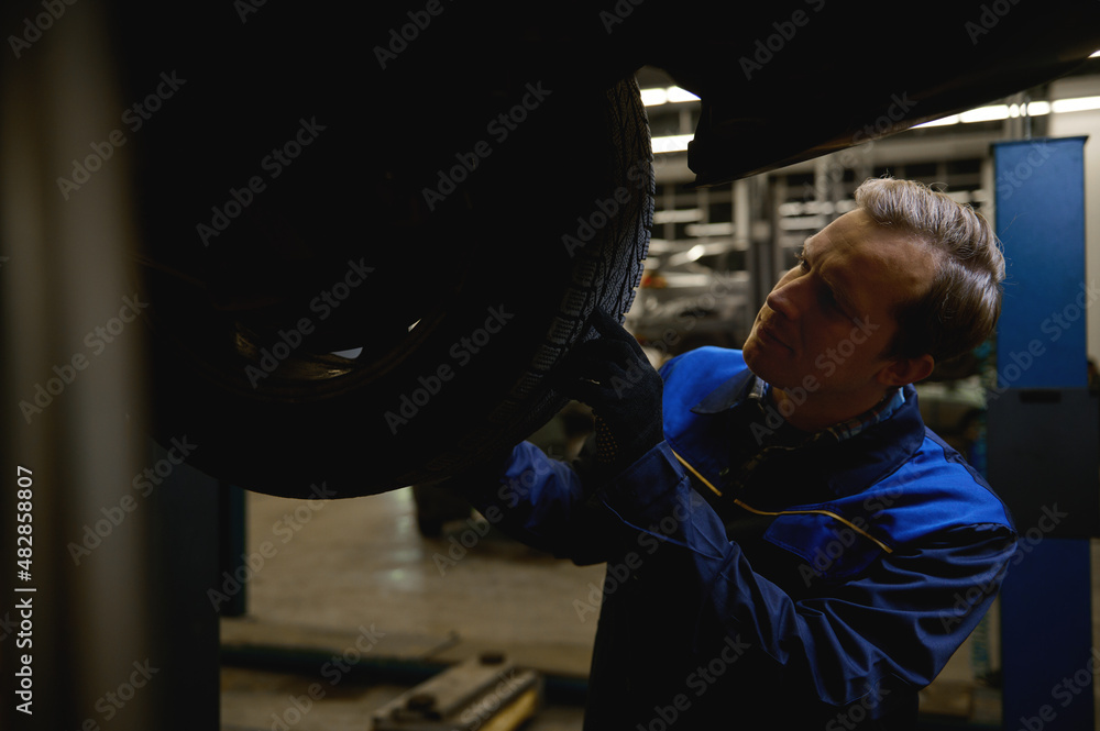 Close-up of a mechanic checking tire in maintenance service center. Technician or engineer professional work for customer, car repair concept Close-up of a mechanic checking tire in maintenance service center. Technician or engineer professional work for customer, car repair concept