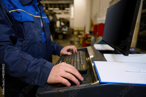 Fotografi Cropped image of technician, engineer, garage mechanic typing on keyboard, makin