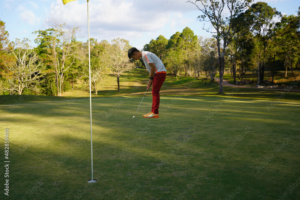 Obraz premium Golf player putting golf ball to hole during sunset or sunrise.