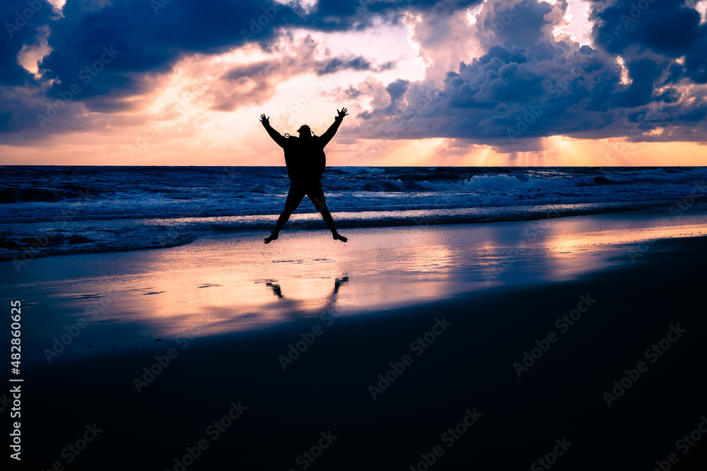 Silhouette of a man jumping with happiness on the beach on vacation.