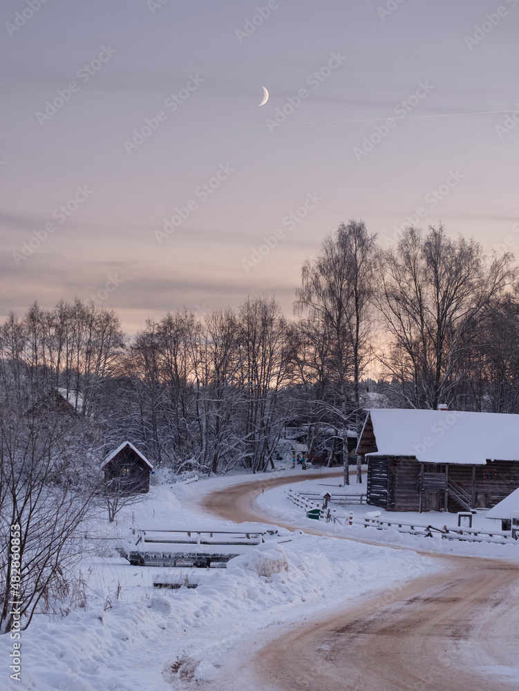 old poor wooden houses and logs under snow on the background. Russian village in winter old poor wooden houses and logs under snow on the background. Russian village in winter