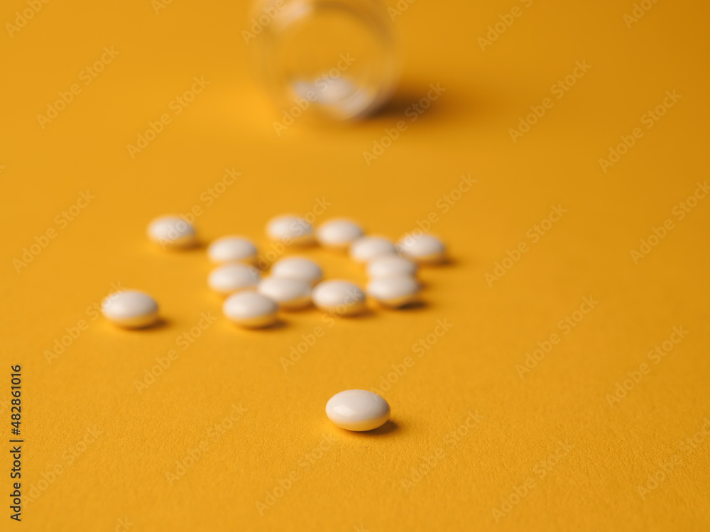 White pills on a yellow background White pills on a yellow background