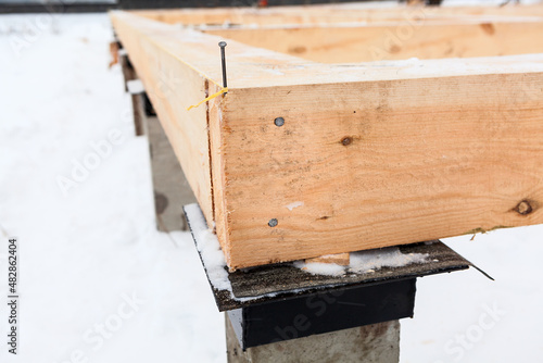 Wooden corner of piled foundation with timber framework beam photo