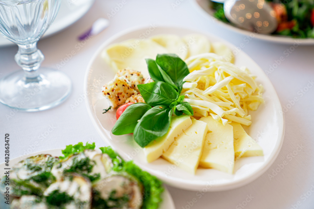 a white plate with sliced cheese. assorted. a white plate with sliced cheese. assorted.