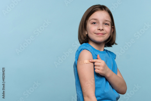Photo Vaccinated Female Child Showing Arm With Adhesive Bandage After Vaccine Injection On Light Blue Background