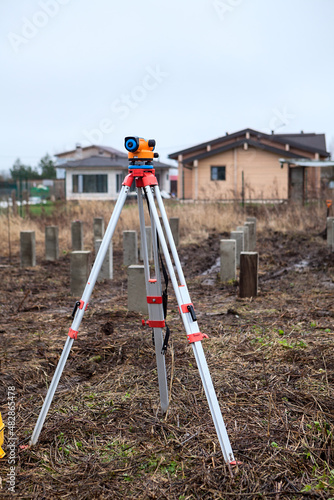 Theodolite stands on a tripod in the middle of the construction site, foundation works