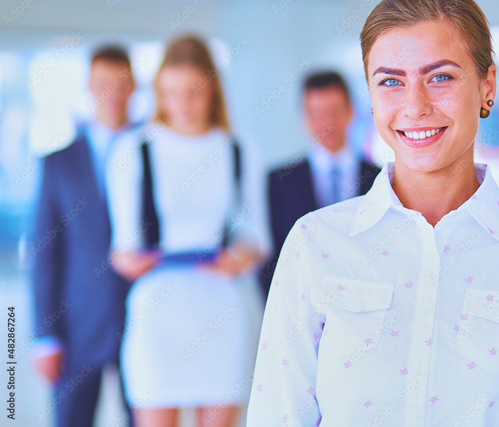 Portrait of young businesswoman in office with colleagues in the background Portrait of young businesswoman in office with colleagues in the background