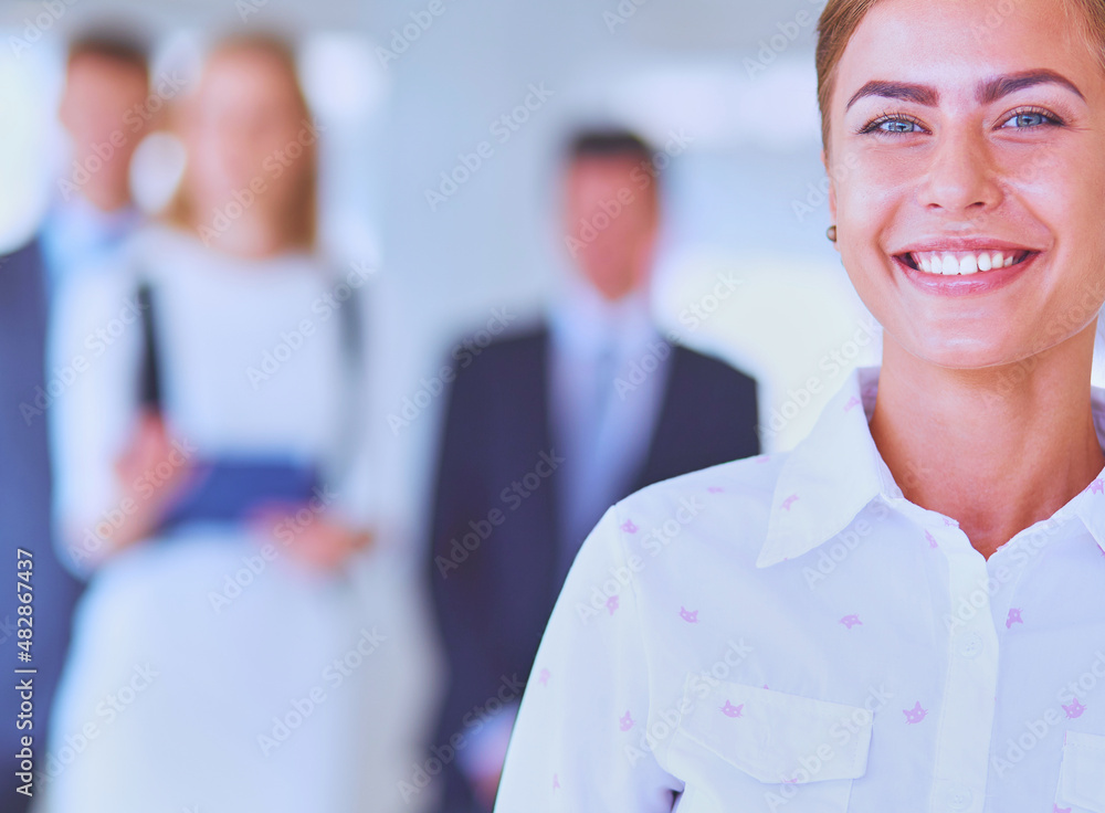 Portrait of young businesswoman in office with colleagues in the background Portrait of young businesswoman in office with colleagues in the background