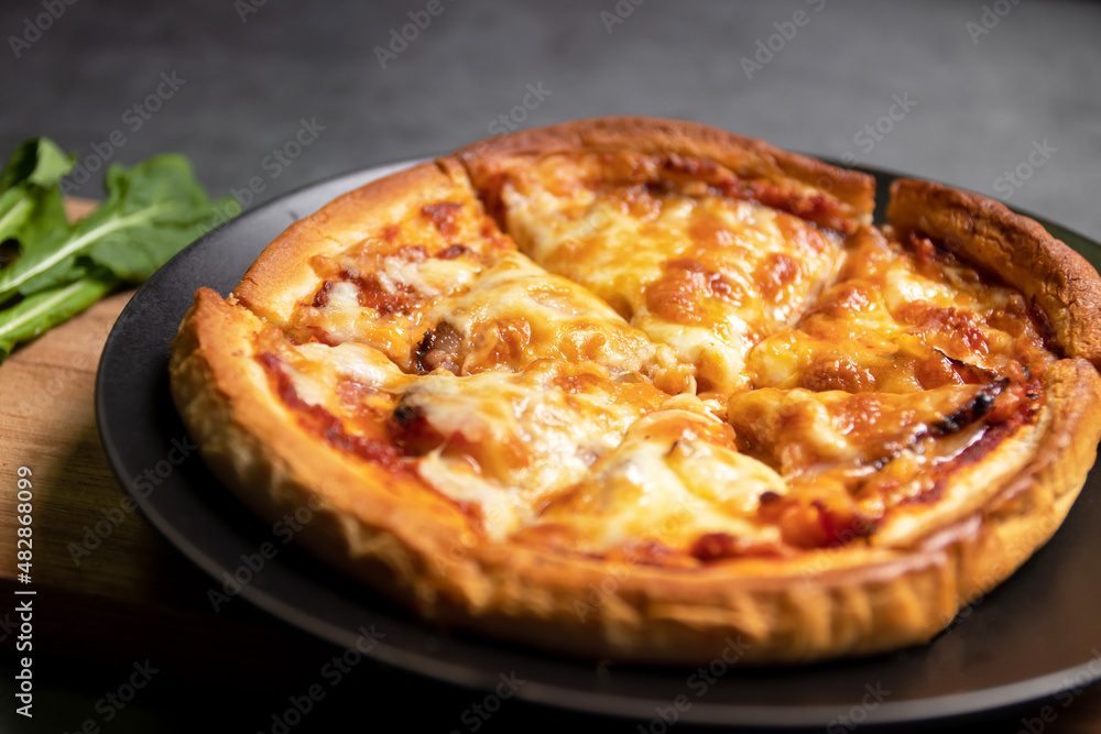 Delicious gourmet pizza with guanciale on wooden board with black table background. Homemade delicious pizza. 