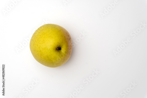 An isolated golden delicious apple with water beads on white background