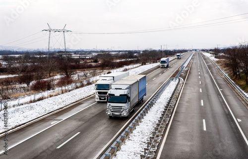 Highway transportation with large Lorry trucks passing trucks in a snowy winter landscape