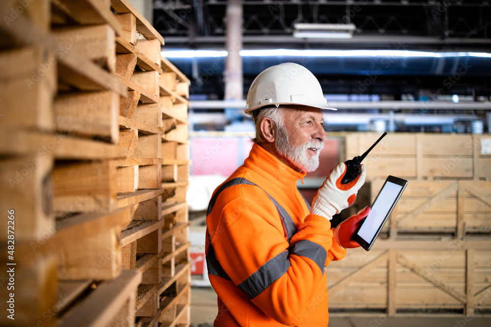 Warehouse worker in safety equipment and hard hat using radio communication and managing goods dispatching. Warehouse worker in safety equipment and hard hat using radio communication and managing goods dispatching.