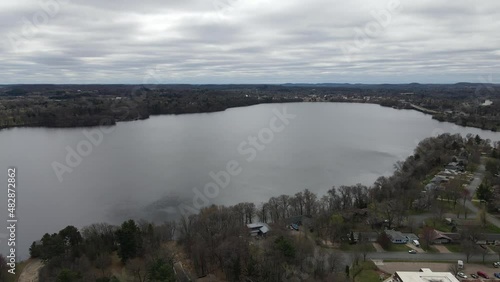 View of Menomonie Lake on a gray cloudy day. Residential neighborhood on the edge of the lake and sprawling city in view. Cool autumn day in Wisconsin.   photo