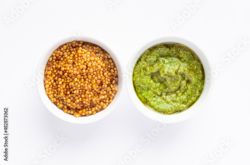 Sauce set - pesto and mustard seeds in gravy bowls isolated on white background