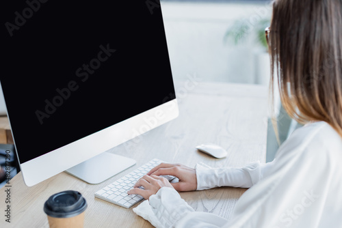 young businesswoman typing on keyboard near computer monitor.