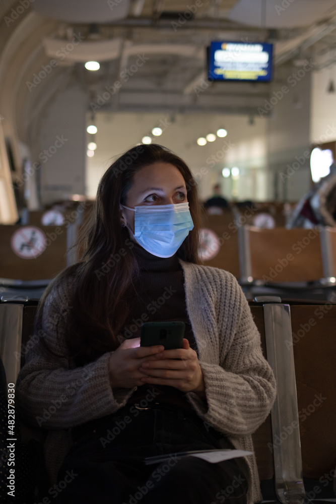 A young woman is sitting in the airport and looking at the table board A young woman is sitting in the airport and looking at the table board