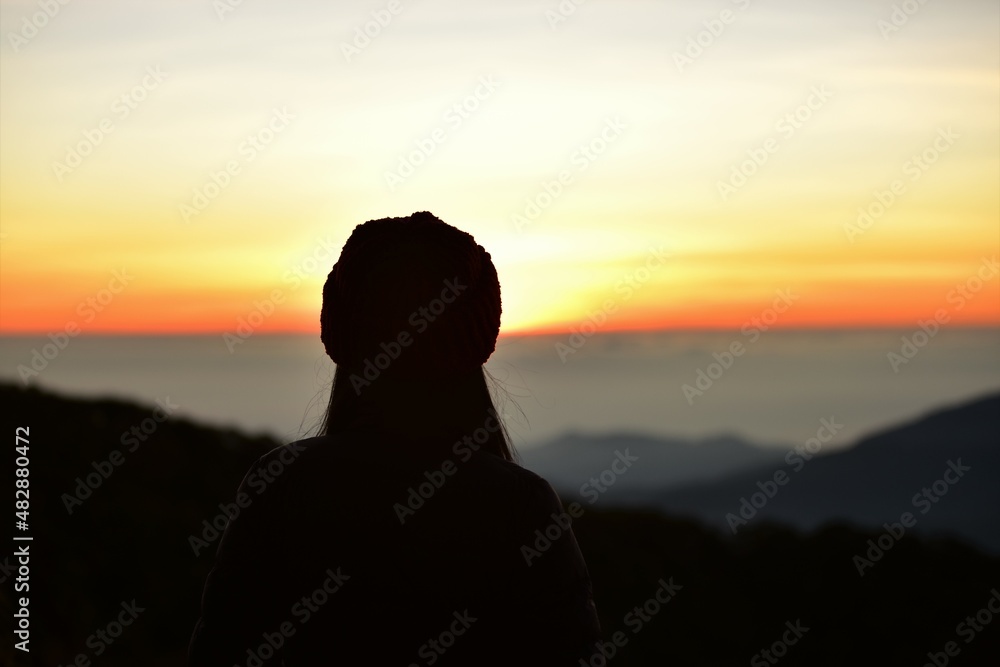 The sun set behind thick forests followed by mountains.