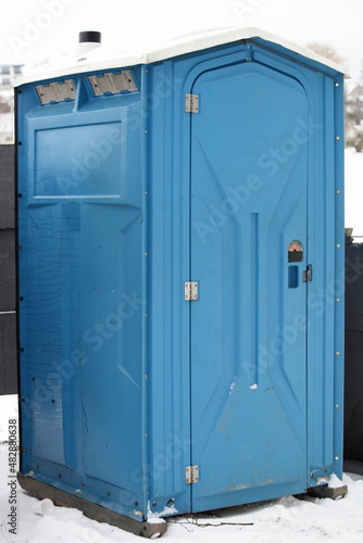 One blue moveable plastic WC cabin close up. Public toilet outdoor on snow at winter photo