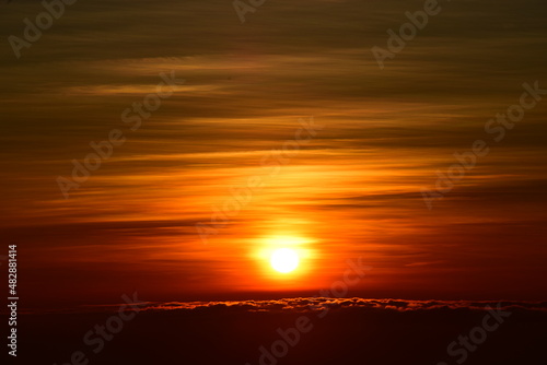 The sun set behind thick forests followed by mountains.