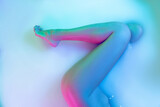 Legs and belly. Close up female body in the milk bath with soft white glowing in neon light. Beauty, fashion, style, bodycare concept. Attractive