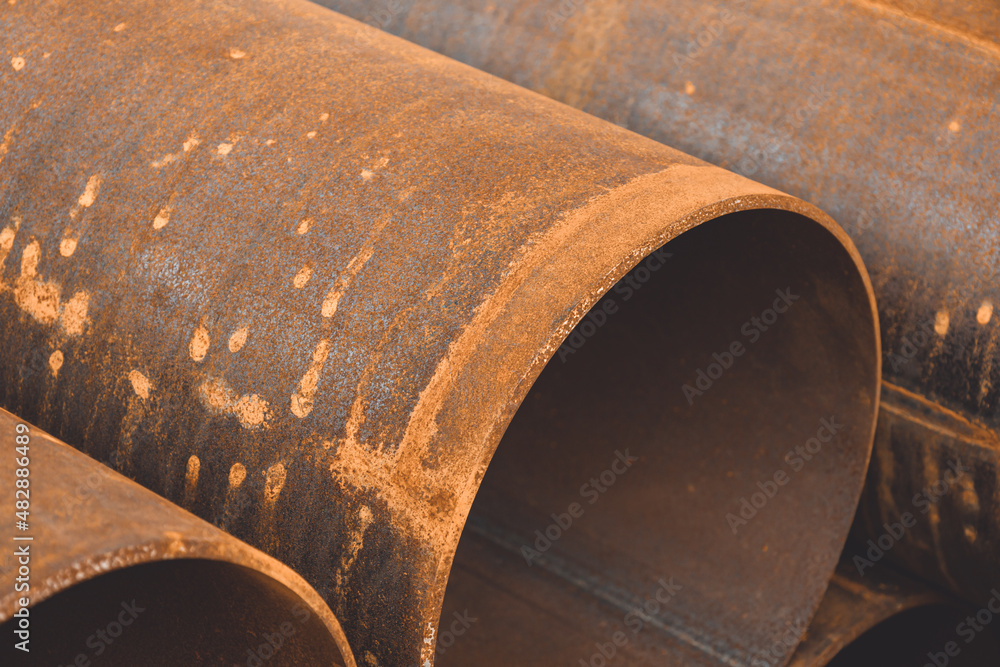 Stack of big rusty steel pipe at a construction site. Installation of pipeline. Metal water tubes. Industrial concept. Soft focus Stack of big rusty steel pipe at a construction site. Installation of pipeline. Metal water tubes. Industrial concept. Soft focus