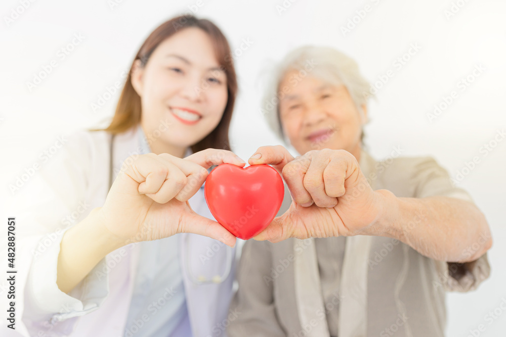 close up hands and blur people, asian female doctor and old patient holding red heart with hands, happiness and relationship in hospital, they feeling happy and smile on white background close up hands and blur people, asian female doctor and old patient holding red heart with hands, happiness and relationship in hospital, they feeling happy and smile on white background