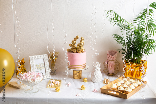 Holiday birthday table with cake and ballons. Pink and golden decoration
