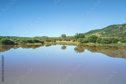 Landscape view of a lake surrounded by mountains and green savanna grassland, Pilanesburg Nature Reserve, North West Province, South Africa