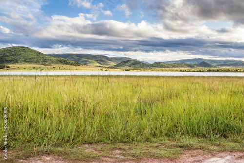 Landscape view of a lake surrounded by mountains and green savanna grassland  Pilanesburg Nature Reserve  North West Province  South Africa