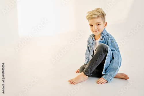 little boy with blonde hair sitting on a white background