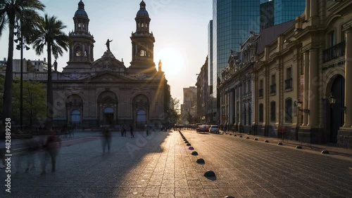 Zoom out time lapse view of sun setting behind historical landmark Santiago Metropolitan Cathedral at Plaza de Armas square in Downtown Santiago, the capital and largest city of Chile.