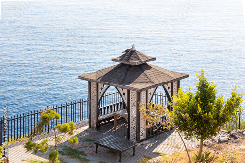 Beautiful wooden pavilion and green plants are on the beach by the blue sea