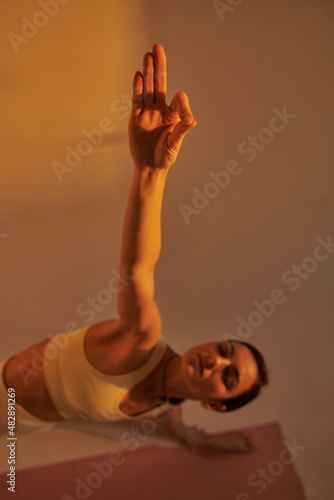 young woman doing yoga poses in studio on white background, sunset light