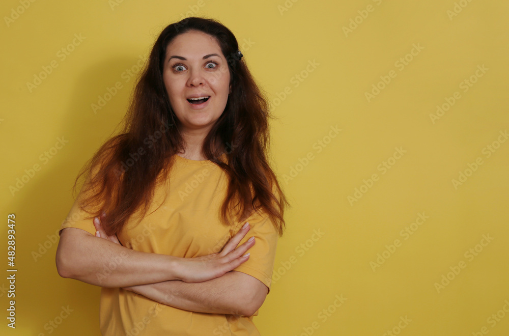 Obraz premium Joyful and surprised woman in a yellow tank top with long dark hair.