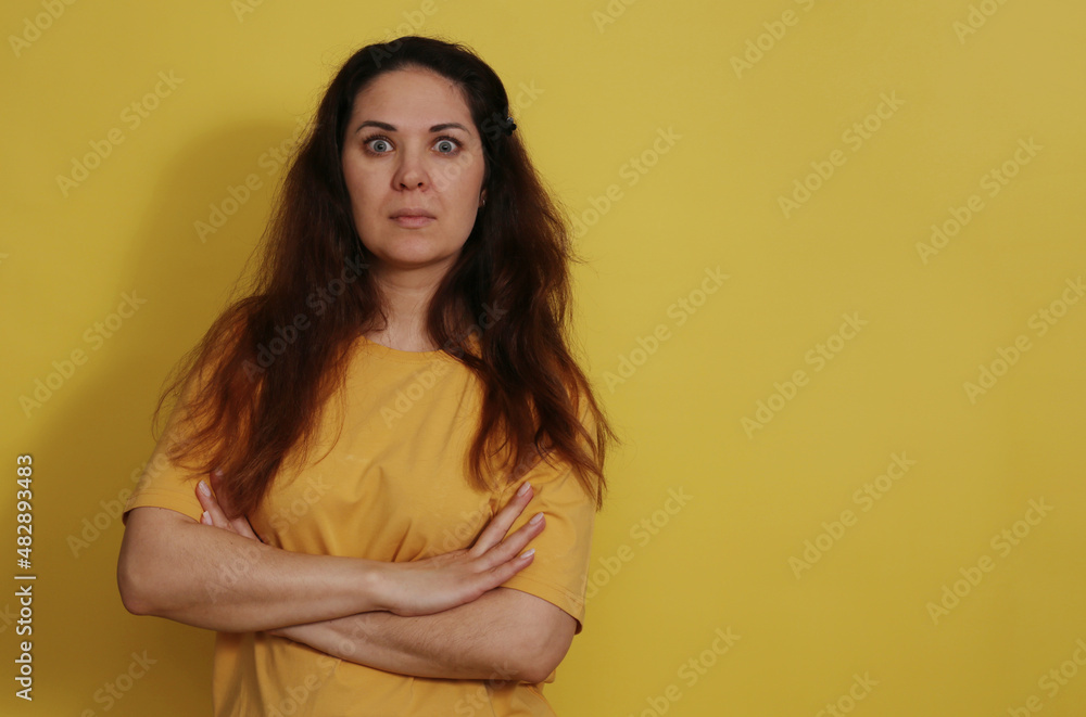 Obraz premium Close up portrait of a surprised woman in a yellow t-shirt on a studio background.