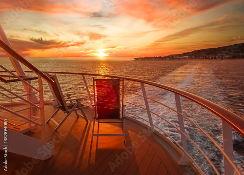 Vue de deux chaises longues sur le pont d'un navire de croisière au coucher de soleil dans le sillage du navire de croisière. Vue depuis la poupe du navire.  © ODIN Daniel