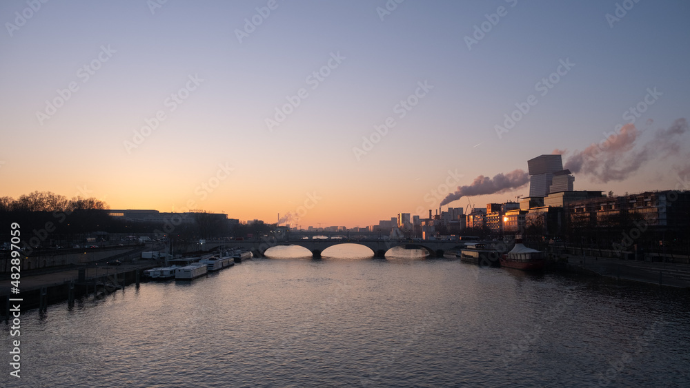 Bridge over the Seine at sunrise in Paris, with a smoke at the horizon