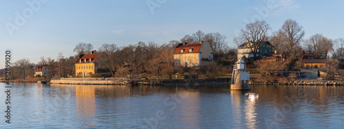 Panorama view over old houses and a lighthouse with a speed sign by the water front at the ness Blockhusudden a sunny winter afternoon in Stockholm 