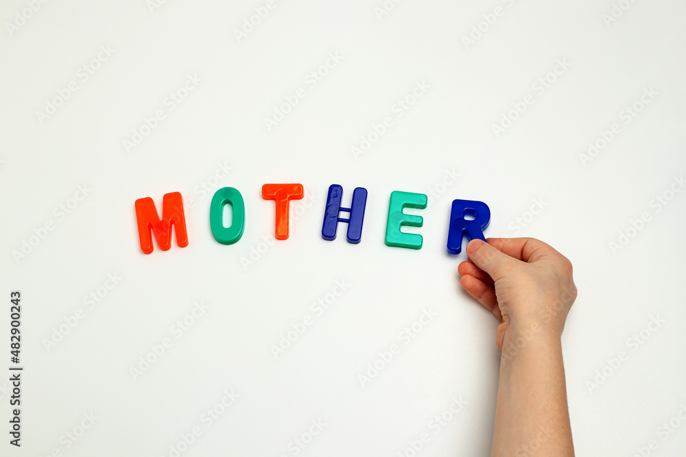 The child's hands and the word mother made of multicolored letters The child's hands and the word mother made of multicolored letters