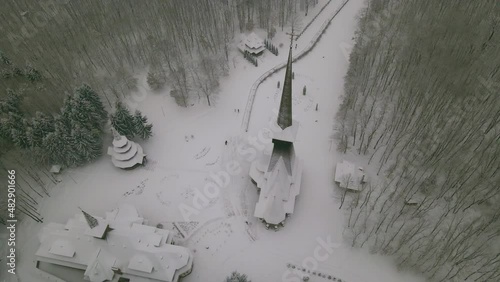 Aerial footage of the wooden church at Sapanta-Peri in Maramures county, Romania in winter. Video was shot from a drone while picking altitude and flying backwards, tilting the camera up to reveal the